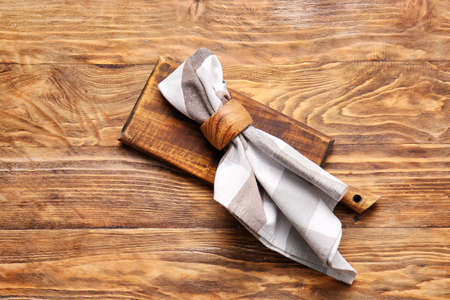 Fabric napkin and board on wooden background