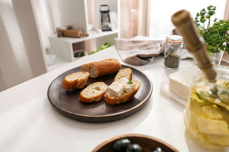 Plate of tasty bruschettas with feta cheese on table in kitchenの写真素材
