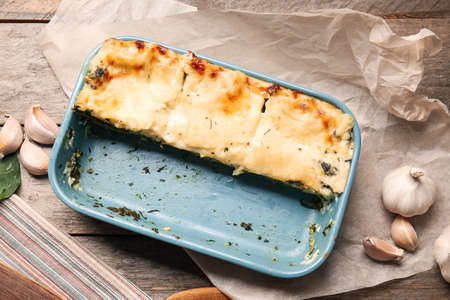 Baking dish with tasty green lasagna on wooden backgroundの写真素材