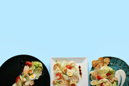 Plates with Caesar salad on color backgroundの写真素材