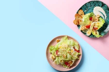 Plates with delicious Caesar salad on color backgroundの写真素材