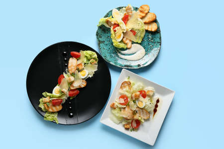 Plates with Caesar salad on color backgroundの写真素材