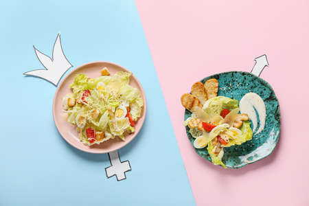 Creative composition with gender symbols and plates with Caesar salad on color backgroundの写真素材