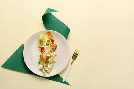Plate with Caesar salad and napkin on color backgroundの写真素材