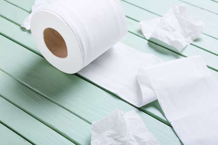 Roll of toilet paper and crumpled sheets on color wooden backgroundの写真素材