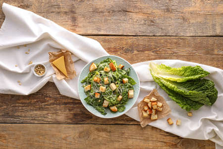 Plate with tasty Caesar salad on wooden backgroundの写真素材