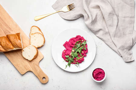 Plate with tasty beet hummus, fresh sprouts and bread on light backgroundの写真素材
