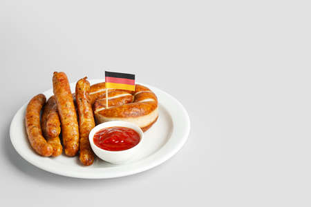 Plate with tasty sausages, sauce and flag of Germany on light backgroundの写真素材