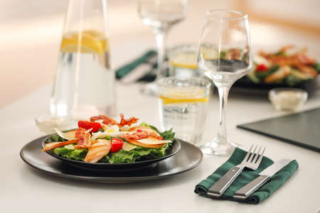 Plate with tasty Caesar salad on table in restaurantの写真素材