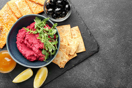 Composition with tasty beet hummus, crackers, olives and sauce on dark backgroundの写真素材