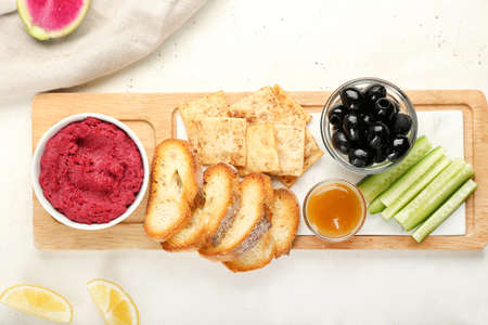 Board with tasty beet hummus and snacks on light backgroundの写真素材