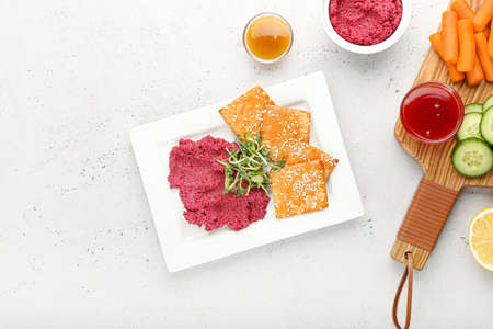 Composition with tasty beet hummus, snacks and sauces on light background