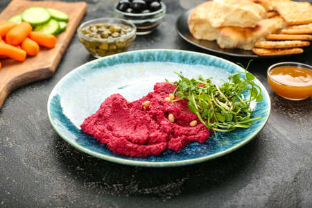 Plate with tasty beet hummus and fresh sprouts on dark backgroundの写真素材