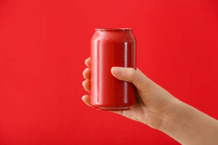 Hand with can of soda on color backgroundの写真素材