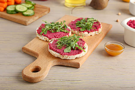 Rice crackers with tasty beet hummus and fresh sprouts on gray wooden backgroundの写真素材