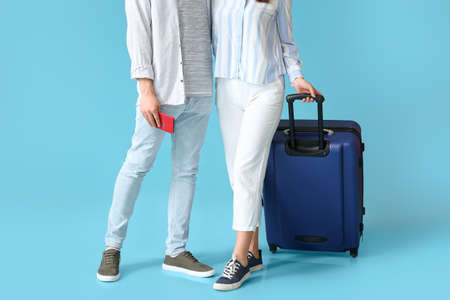 Couple of tourists with luggage on color backgroundの写真素材