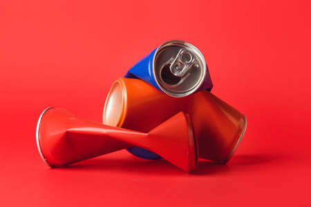 Crumpled cans of soda on color background