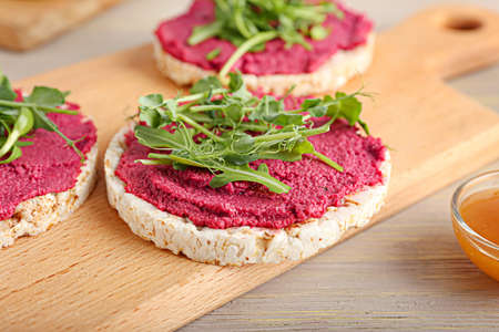 Rice crackers with tasty beet hummus and fresh sprouts on gray wooden background, closeupの写真素材