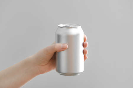 Hand with can of soda on gray backgroundの写真素材