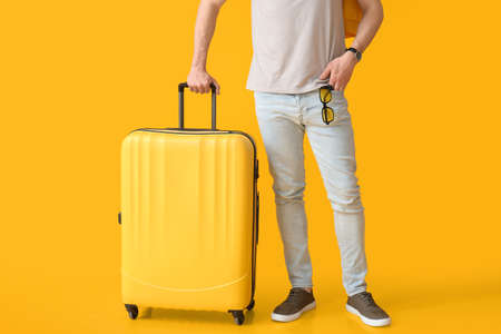 Male tourist with luggage on color backgroundの写真素材