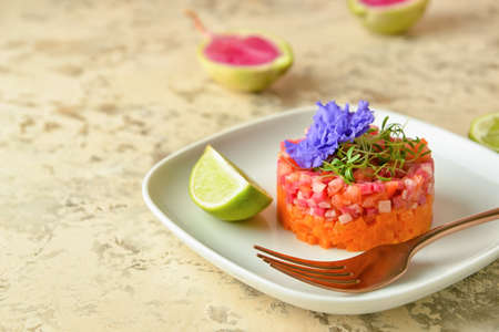 Plate with tasty tartare salad, lime and flower on color background, closeupの写真素材