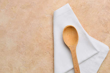 Fabric napkin and wooden spoon on color backgroundの写真素材