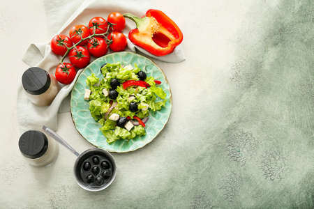 Plate with fresh Greek salad and ingredients on grunge backgroundの写真素材