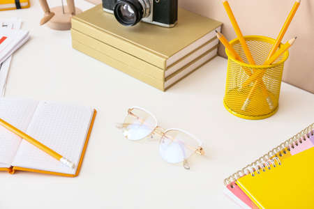 Stylish eyeglasses with pencils and books on tableの写真素材