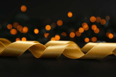 Golden ribbon on dark background with glowing lightsの写真素材