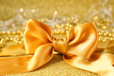 Golden ribbon bow on shiny color backgroundの写真素材