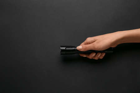 Female hand with modern flashlight on dark background