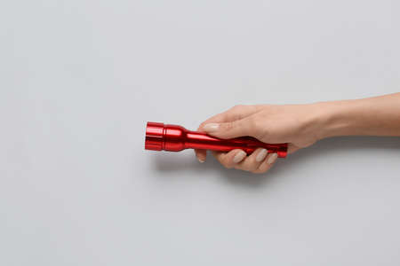 Female hand with modern flashlight on light background