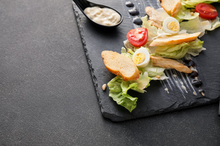 Plate with tasty Caesar salad and sauce on dark background, closeupの写真素材