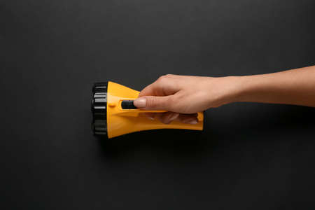 Female hand with modern flashlight on dark backgroundの写真素材