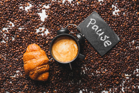 Alarm clock with hot coffee, croissant and word PAUSE on beans