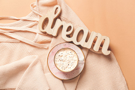 Cup of coffee with word DREAM and sweater on color backgroundの写真素材