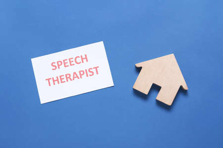 Paper with text SPEECH THERAPIST and house figure on color backgroundの写真素材
