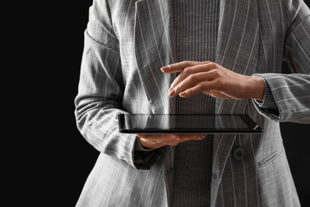 Young woman using tablet computer on dark backgroundの写真素材