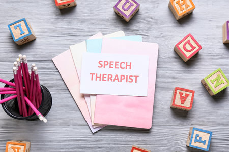 Paper with text SPEECH THERAPIST, stationery and cubes on gray wooden backgroundの写真素材