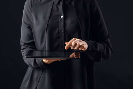 Young woman using tablet computer on dark backgroundの写真素材