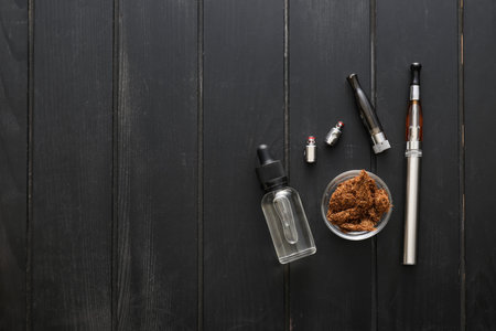 Electronic cigarette with oil and tobacco on dark wooden background
