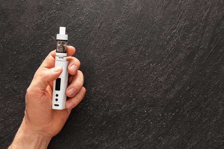 Male hand with vape mod on dark background