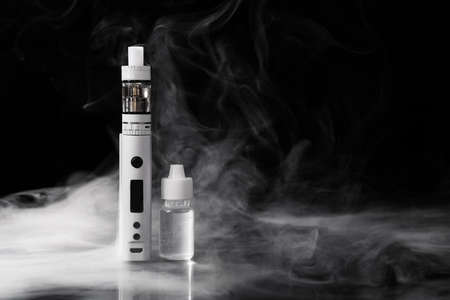 Vape mod with oil on dark background with fume