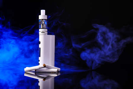 Vape mod with cigarettes on dark background with fume