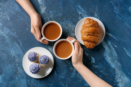 Female hands and cups of coffee with food on grunge backgroundの写真素材