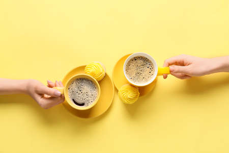 Female hands and cups of coffee with cupcakes on color backgroundの写真素材