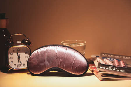 Sleeping mask with pills and magazines on dark backgroundの写真素材