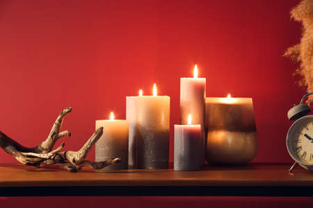 Burning candles and decor on table near color wallの写真素材