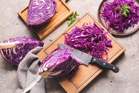 Board with cut fresh purple cabbage on grunge background
