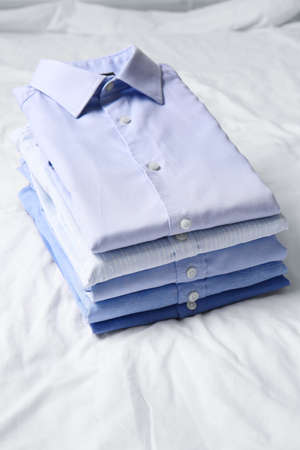 Stack of stylish male shirts on fabric background